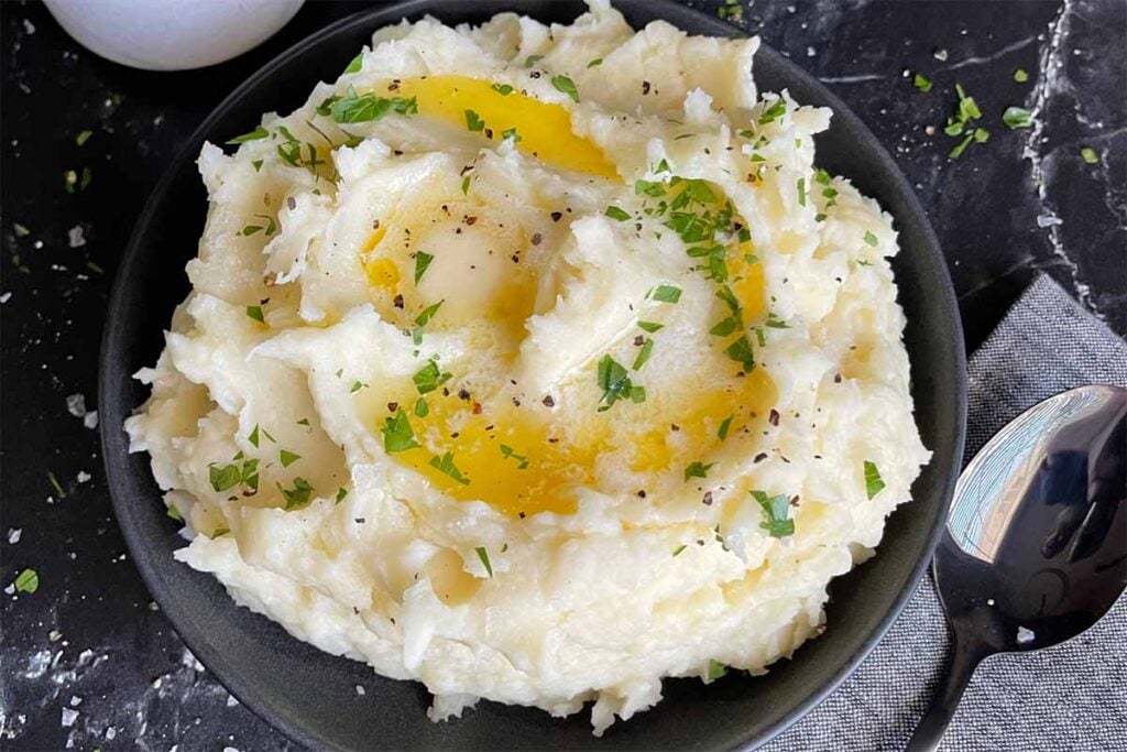 Mashed potatoes with butter in a dark bowl