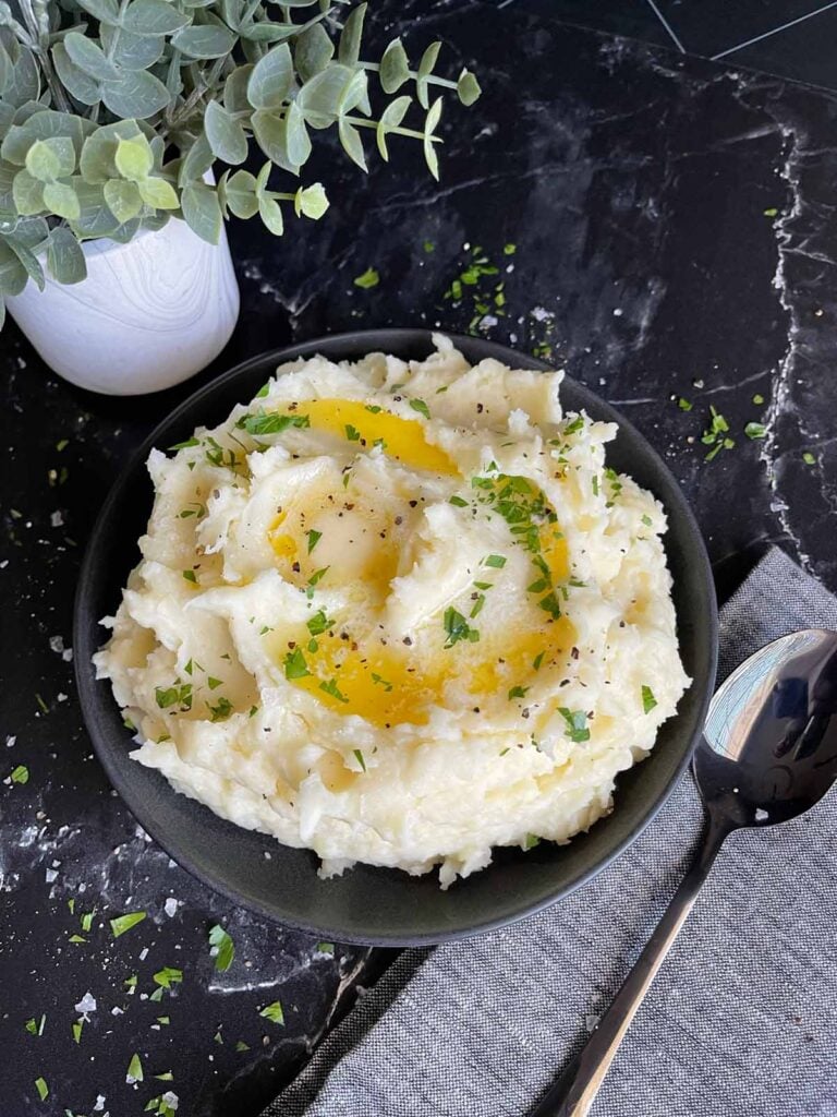Mashed potatoes in a black bowl with butter