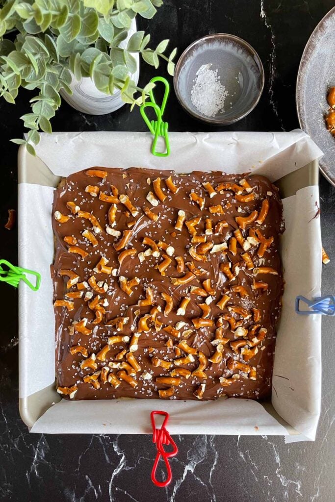 Peanut butter pretzel bars in a parchment lined baking pan.