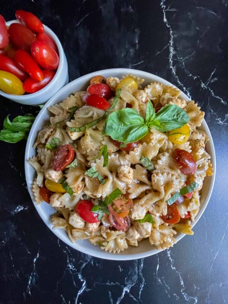 Pesto Caprese Pasta Salad with some tomatoes as a garnish.