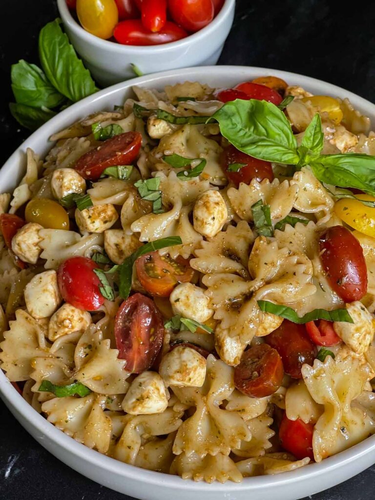 Pesto caprese pasta salad in a white bowl.