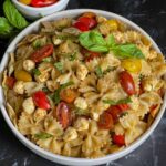 Pesto pasta Caprese salad in a white bowl.