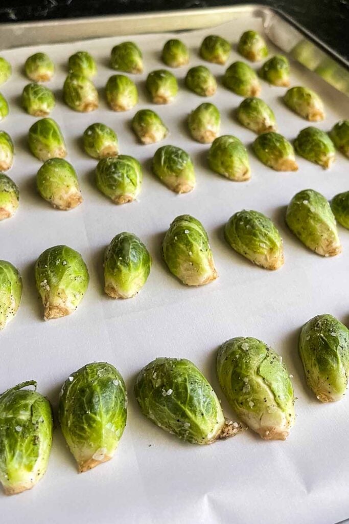 Raw brussels sprouts on a baking sheet.