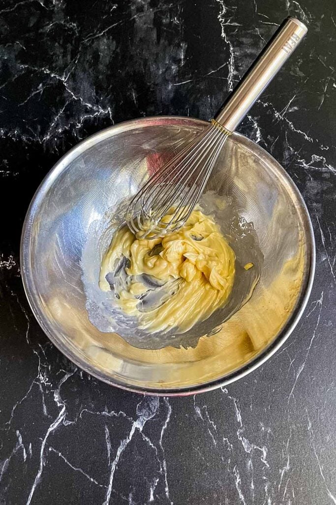 Honey butter in a stainless steel bowl with a whisk.
