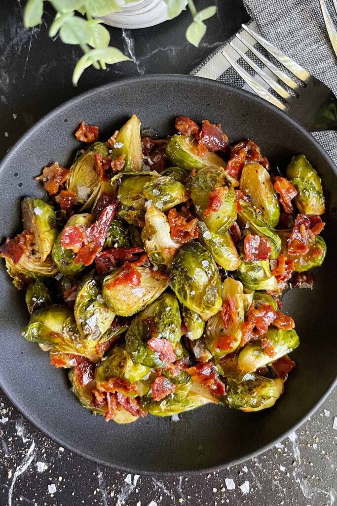 A bowl of Roasted brussels sprouts with honey butter and bacon.