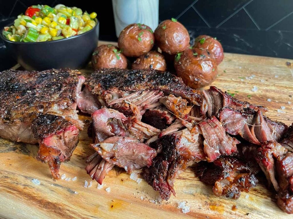 smoked chuck roast with grilled potatoes and succotash on a wooden board