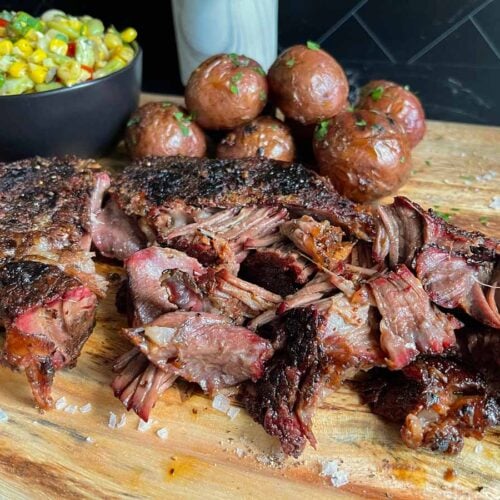 Smoked chuck roast with grilled potatoes and succotash on a wooden board.