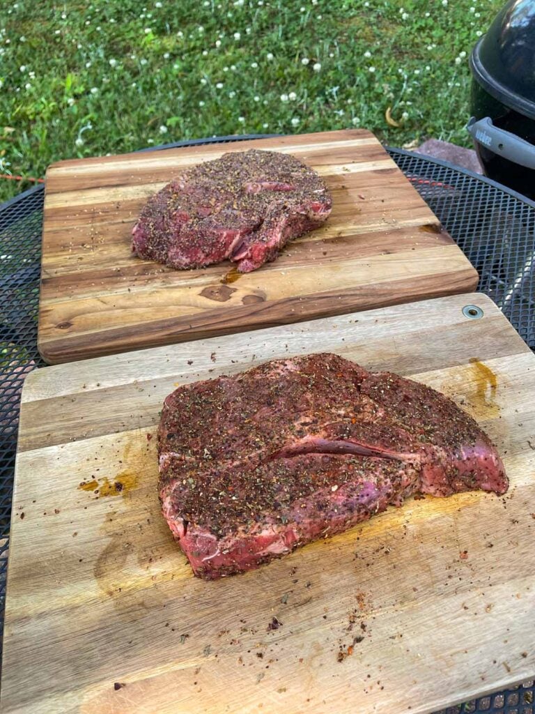 two chuck roasts with rub applied about to go onto a smoker.