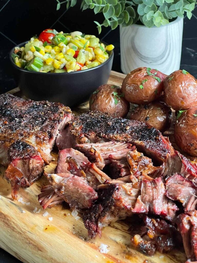 A board full of smoked chuck roast, grilled potatoes, and summer succotash.