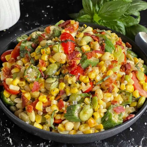 Summer succotash in a black bowl on a dark surface.