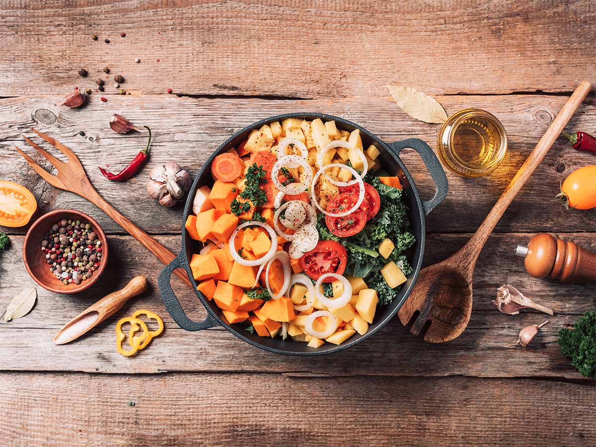 A bowl of vegetables with various kitchen hand tools.