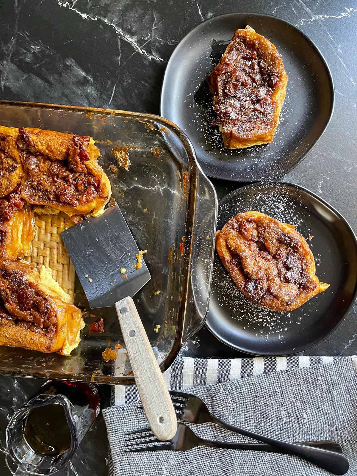 Maple bacon French toast on dark plates on a dark surface.