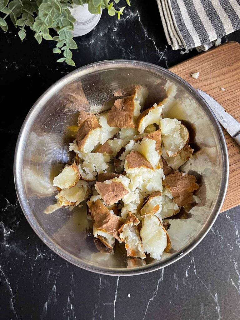 broken up baked potato in a metal bowl.