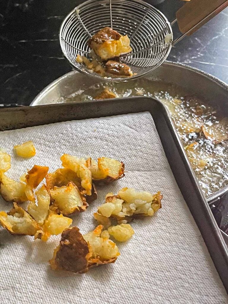 Pulling fried potatoes out of the hot oil.