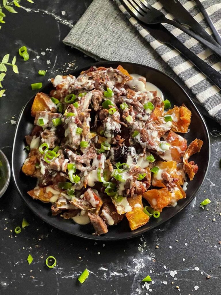 Loaded potato skins on a black plate.