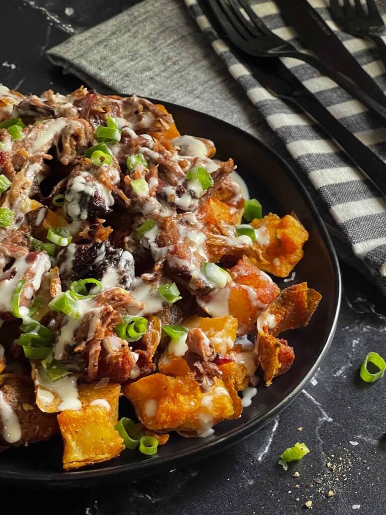 Loaded potato bites on a black plate.