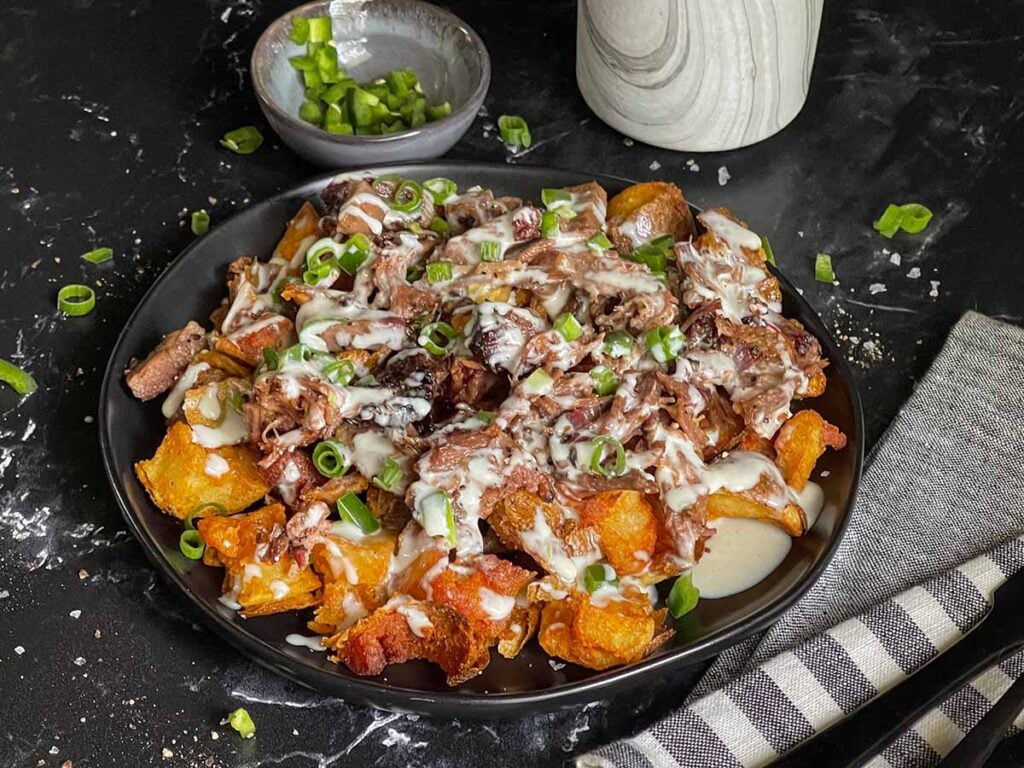 Loaded potato bites on a black plate.