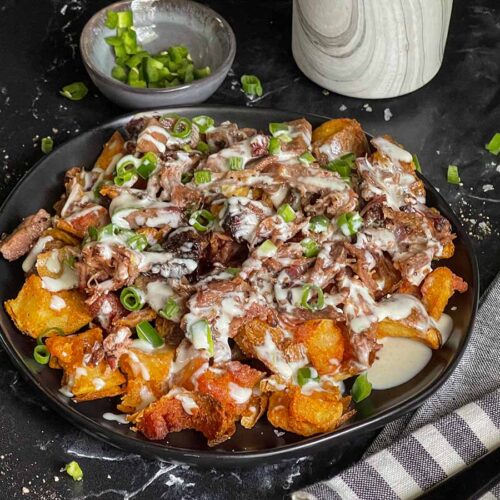 Loaded potato bites on a black plate.