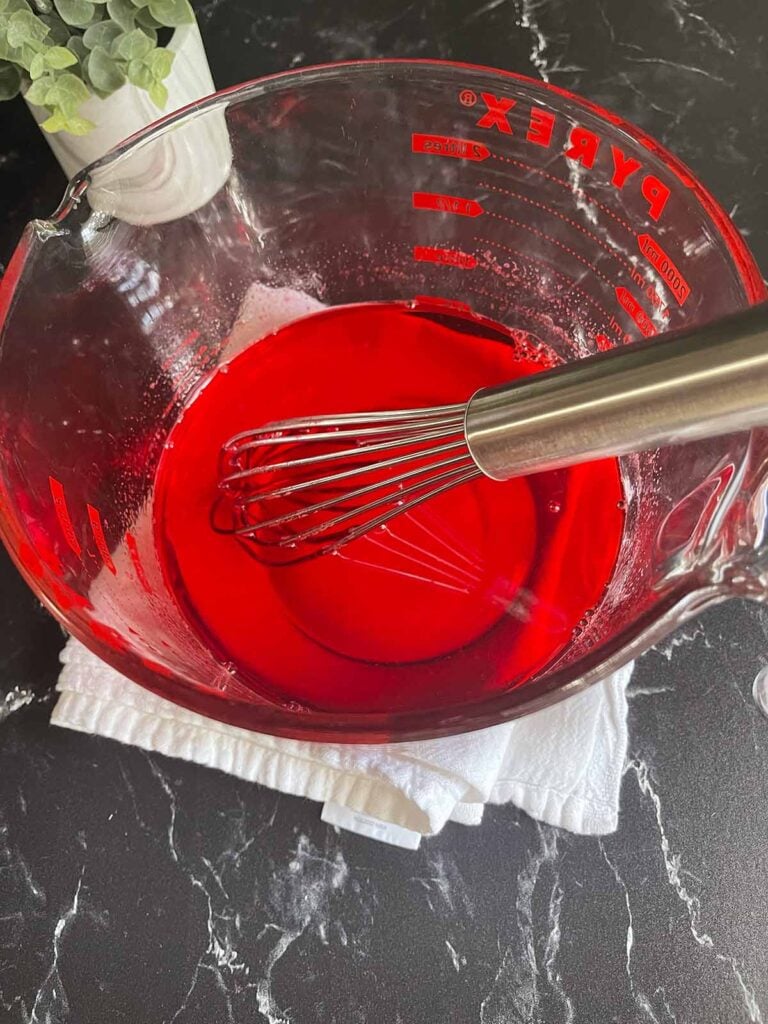 Jello mixed up in a large measuring cup.