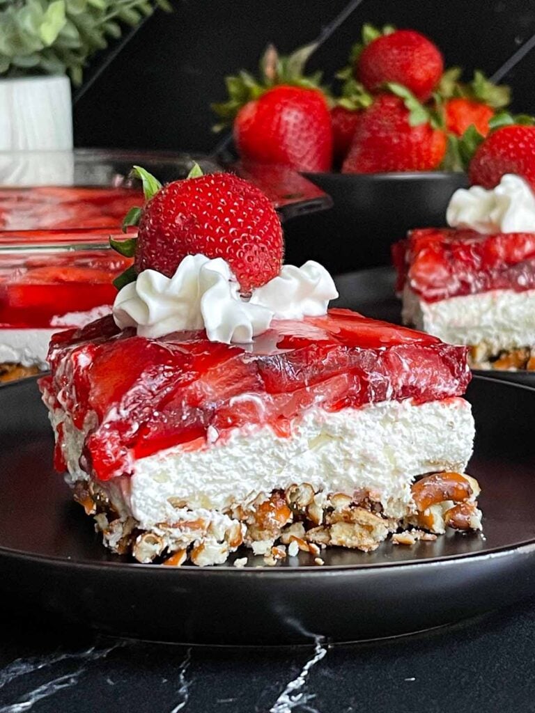 A slice of strawberry pretzel salad on a black plate.