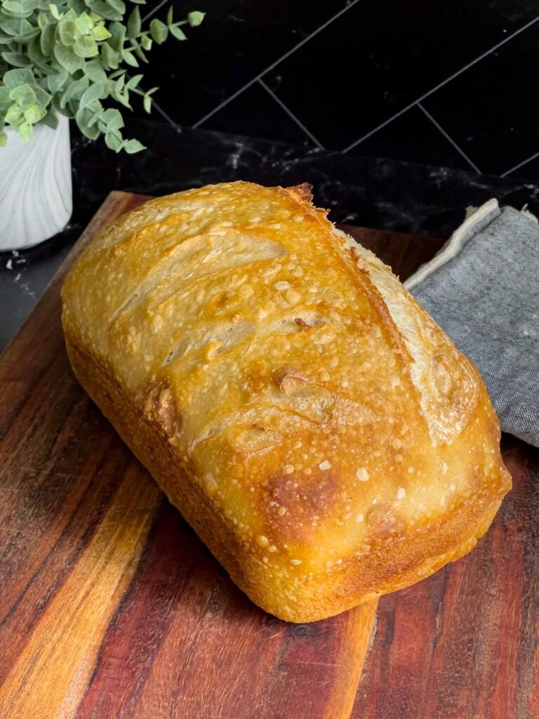 a loaf of sourdough bread on a wood cutting board