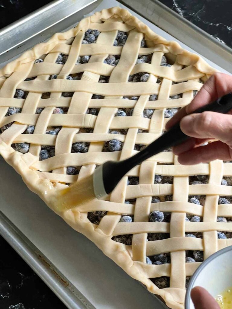 Egg washing the lattice crust for the blueberry slab pie.