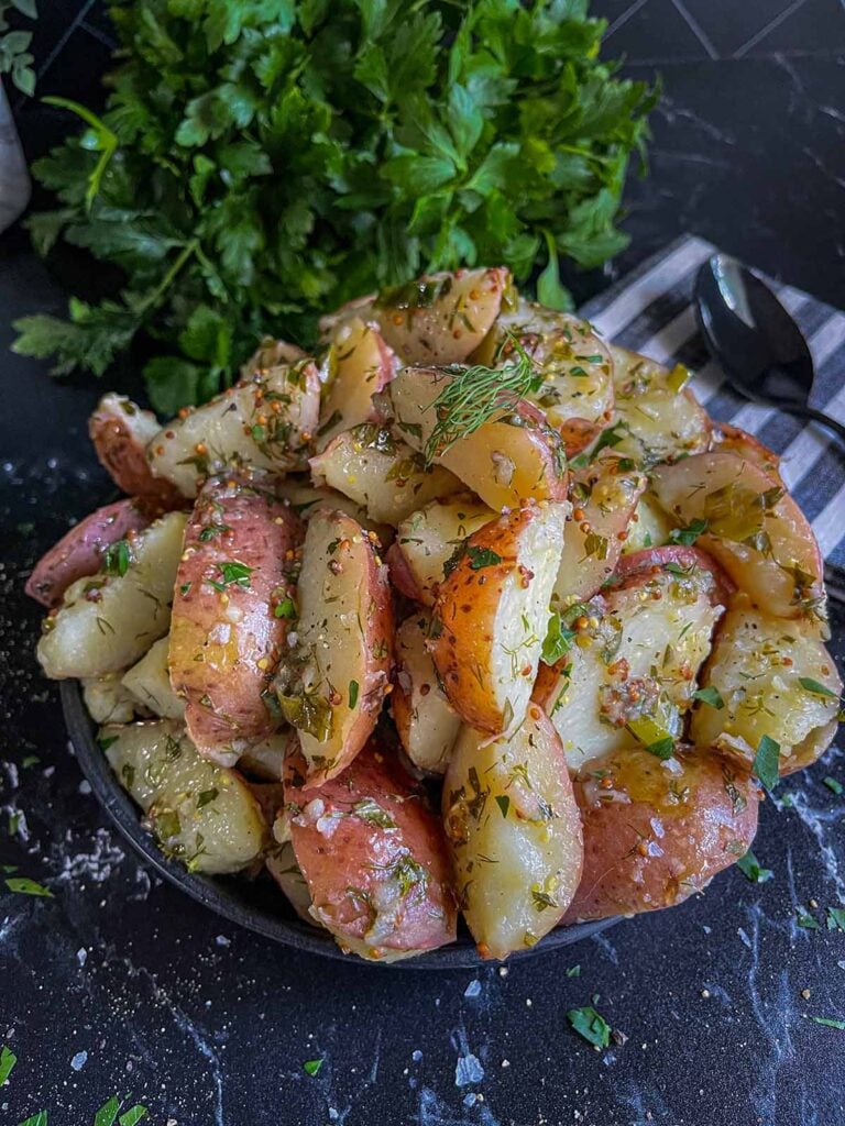 A black plate of herb potato salad.