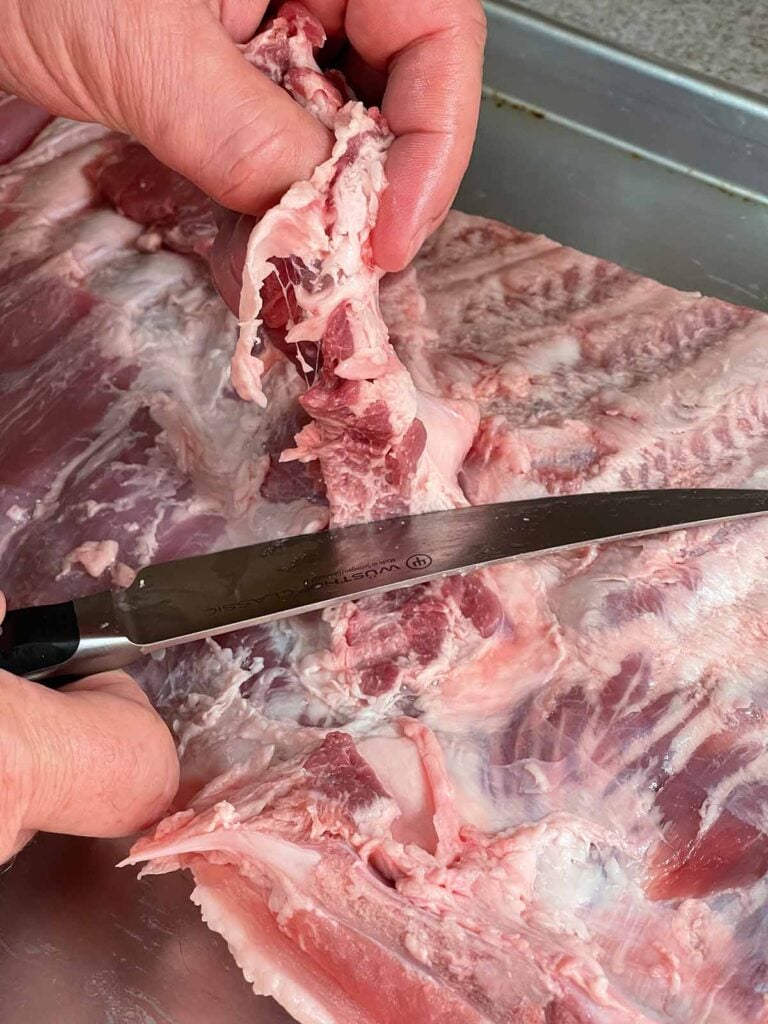 Trimming the diaphragm from the rack of ribs.