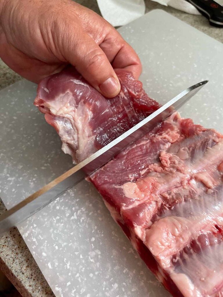 Squaring off the rack of ribs by removing a flap of meat.