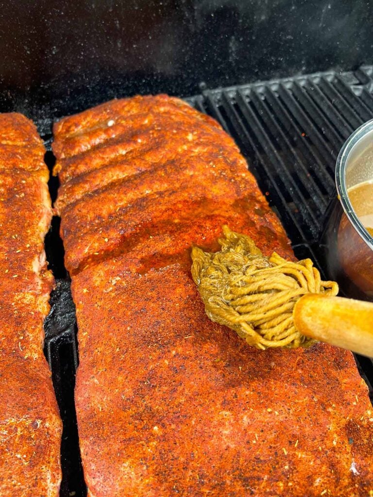 Applying the mop to the ribs on the smoker.