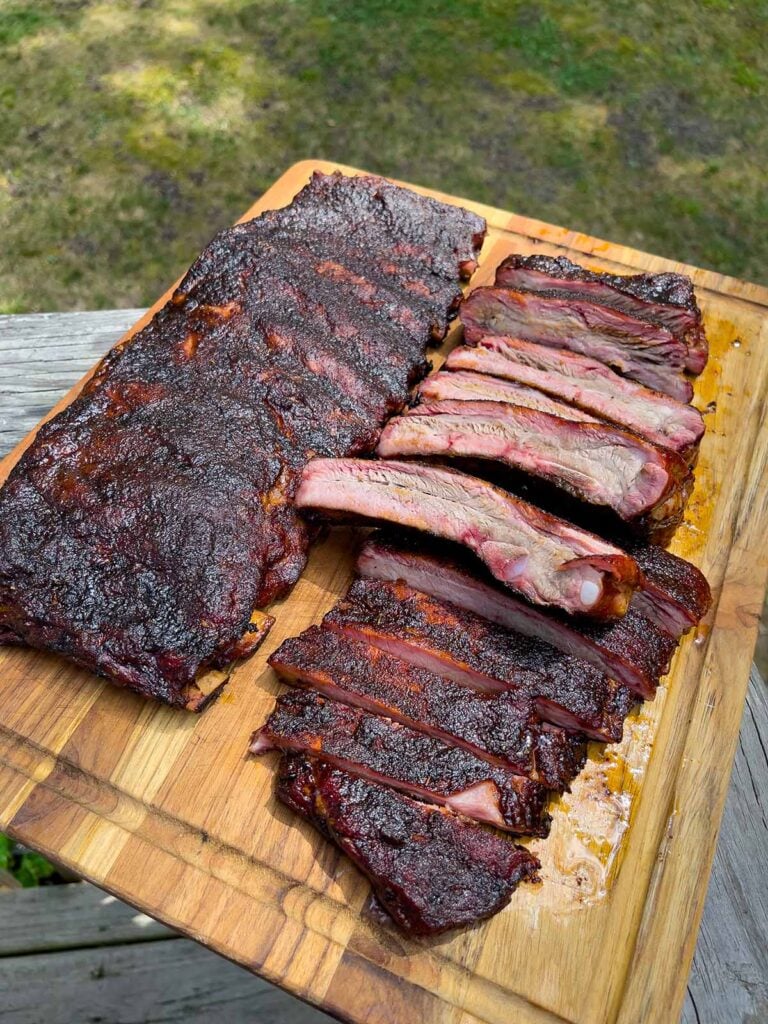 two racks of ribs on a cutting board. One rack has been cut into ribs.