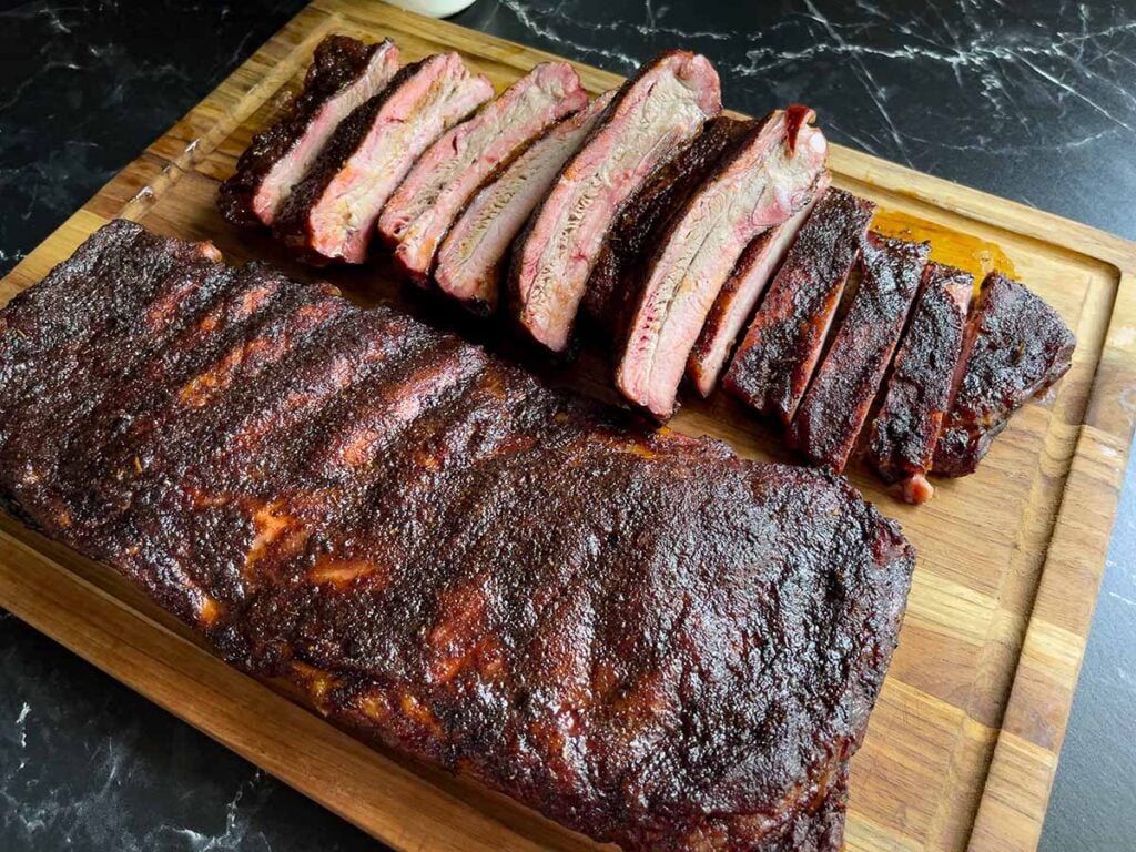 Two racks of st louis style ribs on a cutting board, one cut up.