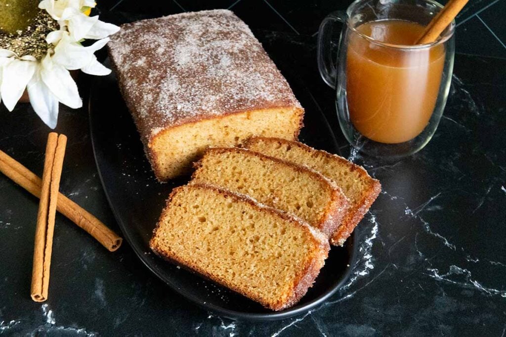 Apple cider doughnut loaf cake on a black plate.