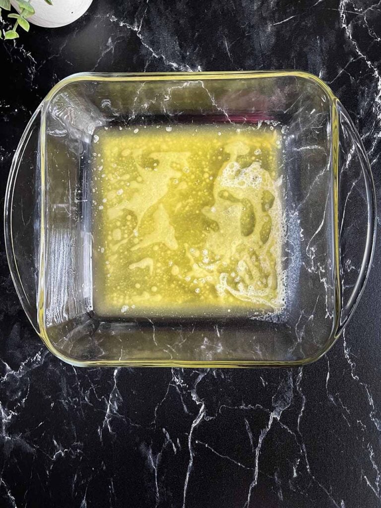 Melted butter in a square glass baking dish.
