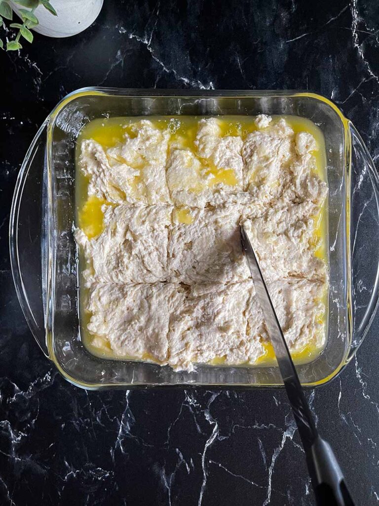 Dough being cut with a knife in the baking dish.