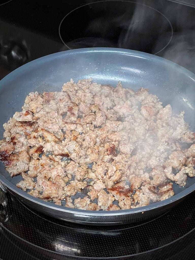 Breakfast sausage browning in a skillet.