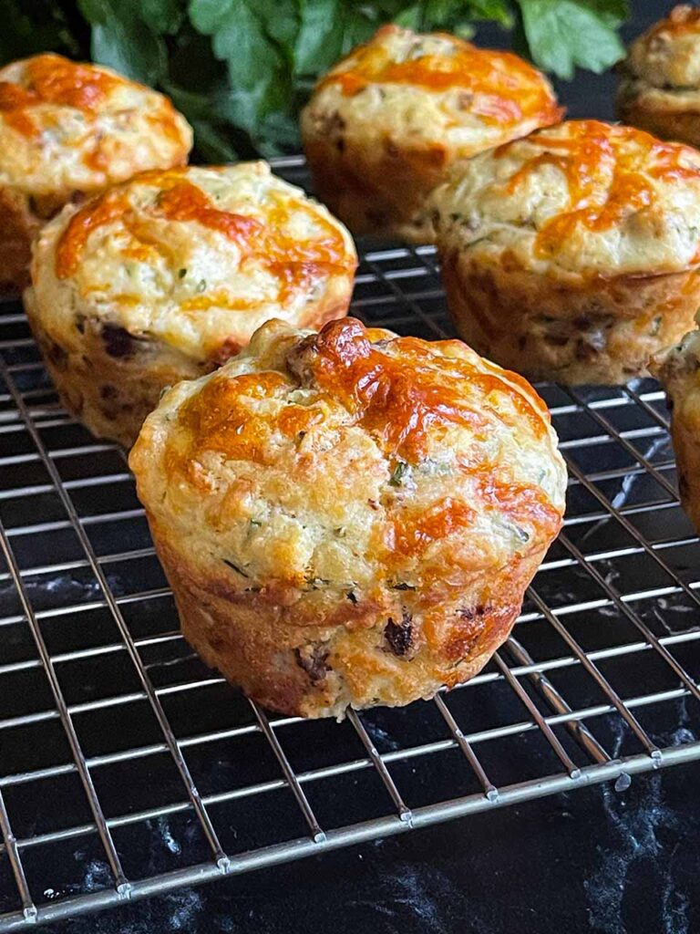 Sausage muffins on a wire rack with a bunch of parsley in the background.