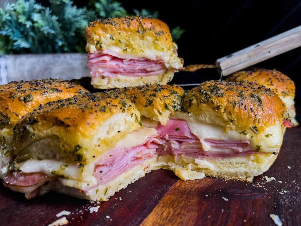 Ham and cheese sliders on a wooden cutting board.