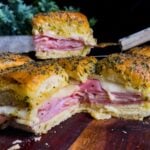 Ham and cheese sliders on a wooden cutting board.