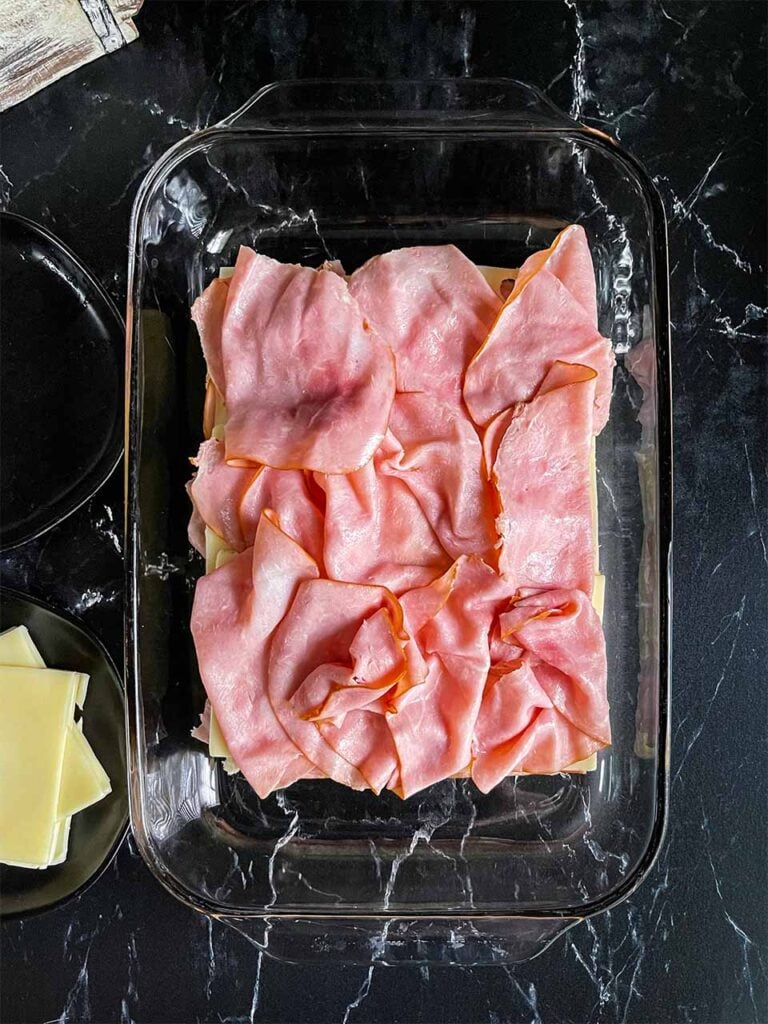 Assembling the sliders in a glass baking dish.