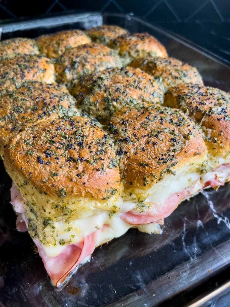 Ham and swiss cheese sliders right out of the oven in a glass baking dish.