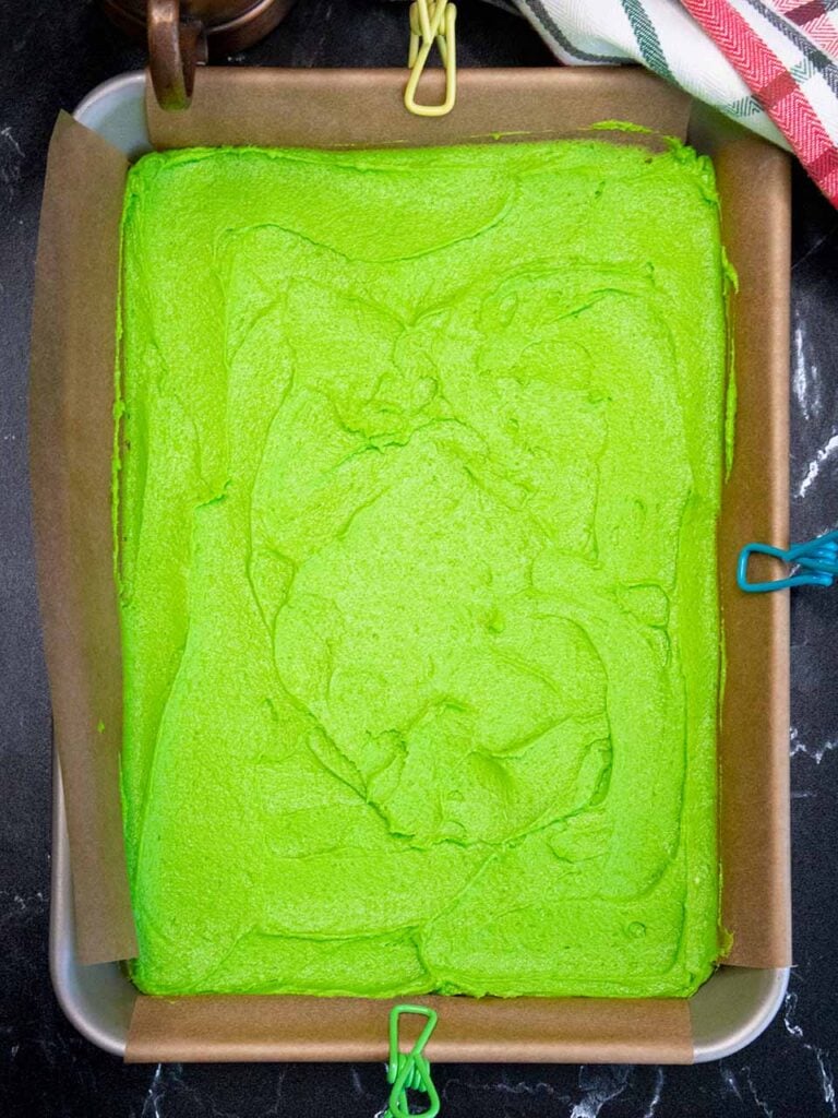 Green cookie dough in the parchment paper lined pan.