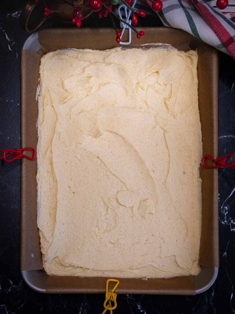 White cookie dough in the parchment paper lined pan.