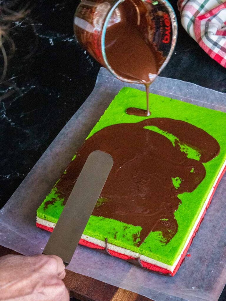 Chocolate being spread over the top of the green layer.