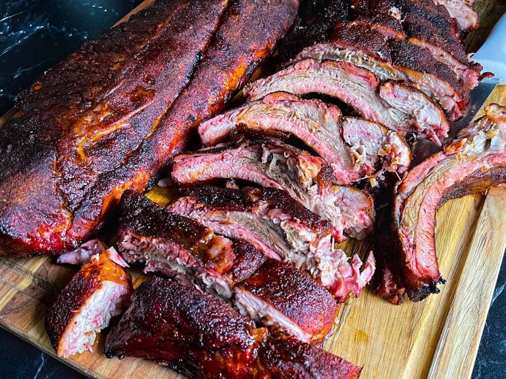 Memphis style baby back ribs cut out and laying on a wooden cutting board.