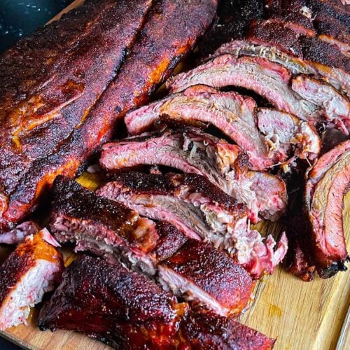 Memphis style baby back ribs laid on on a wooden cutting board.