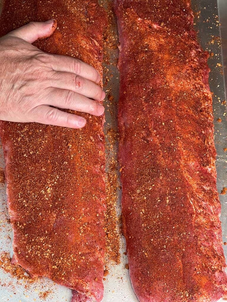 Applying the memphis style rub on baby back ribs.