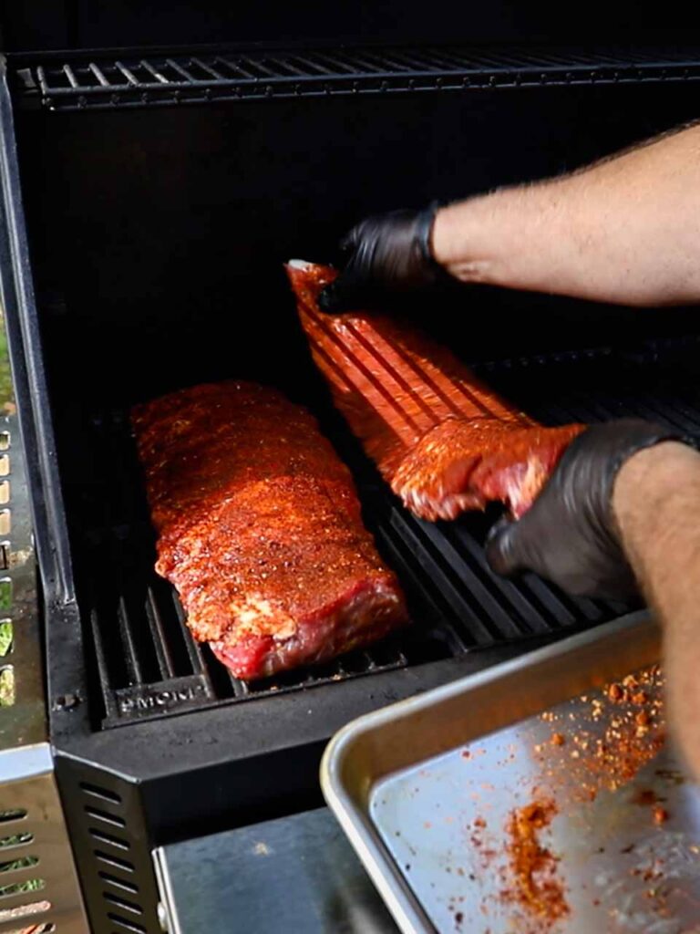 Placing baby back ribs onto the smoker.