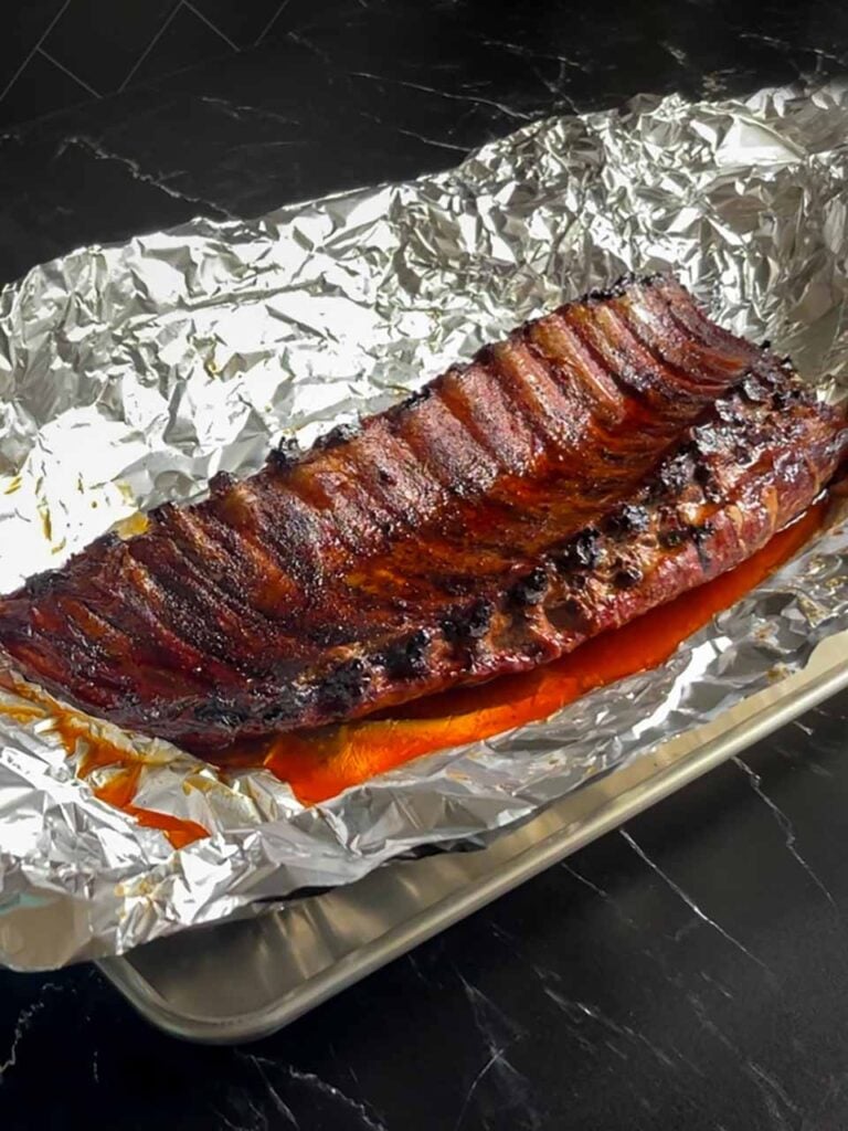 Baby back ribs coming out of the aluminum foil after cooking for an hour or so.