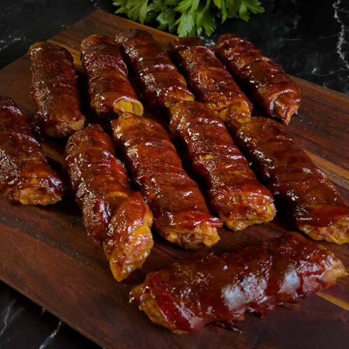 smoked shotgun shells barbecue appetizer on a wooden cutting board.